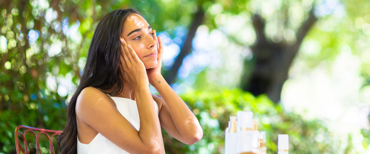 Vrouw verzorgt haar gezicht met Abloom skincare in de tuin