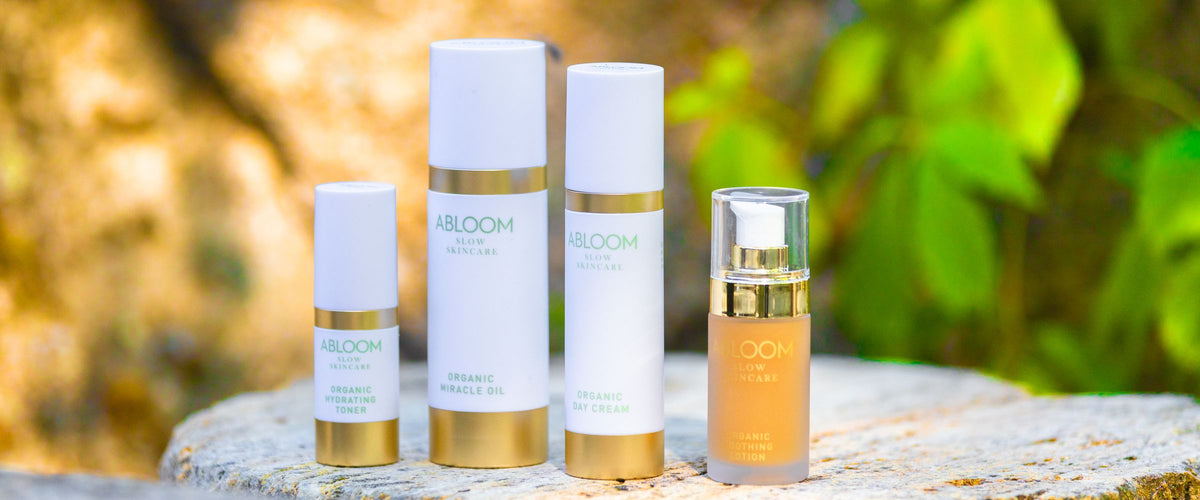 Abloom Hydrating Toner, Miracle Oil, Day Cream en Soothing Lotion op een boomstronk